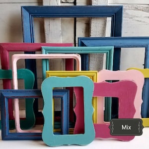 May include: A collection of colorful, empty picture frames in various shapes and sizes. The frames are painted in shades of blue, pink, green, and yellow, with a distressed, vintage finish. The word "Mix" is on a small black label.