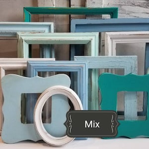 May include: A collection of various painted wooden picture frames in shades of blue, green, and white. The frames have different shapes and styles, including square and oval. The word "Mix" is on a black label.