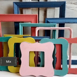 May include: A collection of colorful, distressed wooden picture frames in various shapes and sizes. The frames are painted in shades of coral, teal, yellow, pink, and blue. The word "Mix" is visible on a label.