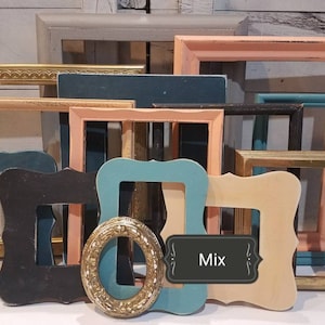 May include: A collection of various picture frames in different colors and styles. Frames include gold, teal, black, peach, and beige. The frames are rectangular, oval, and ornate. A label with the word "Mix" is visible.