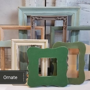 May include: A collection of ornate, empty picture frames in various sizes and colors, including green, blue, and cream. The frames have distressed finishes and decorative details. The word "Ornate" is displayed on a black label.