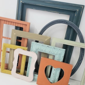 May include: A collection of various colorful picture frames in shades of orange, pink, yellow, green, and blue. The frames are different shapes and sizes, including a heart-shaped frame and a circular frame.