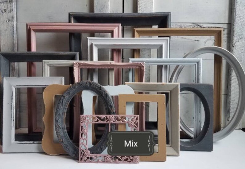 May include: A collection of various picture frames in different shapes, sizes, and colors. The frames include rectangular, oval, and circular designs, with colors like pink, gray, and brown. A small sign with the word "Mix" is visible.