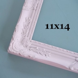 Peut inclure: Cadre photo blanc orn&eacute; avec le texte "11X14". Le cadre pr&eacute;sente des motifs floraux et des volutes d&eacute;taill&eacute;s. Le cadre mesure 28 cm sur 36 cm.
