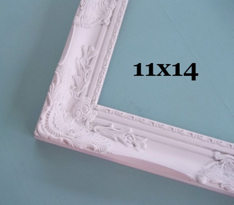 Peut inclure: Cadre photo blanc orn&eacute; avec le texte "11X14". Le cadre pr&eacute;sente des motifs floraux et des volutes d&eacute;taill&eacute;s. Le cadre mesure 28 cm sur 36 cm.