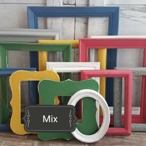 May include: A collection of colorful picture frames in various shapes and sizes. Frames are painted in shades of blue, green, yellow, pink, and gray. An oval white frame and a green frame with a decorative edge are also included. A sign with the word "Mix" is in the center.