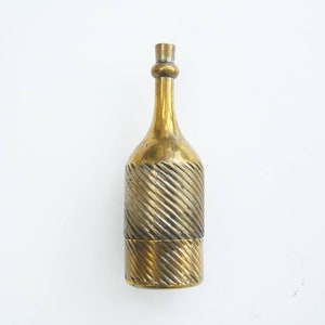 May include: A vintage brass bottle-shaped container. The container has a textured, diagonal-striped pattern on the lower portion and a smooth, slender neck. The bottle is made of brass and has a shiny, golden appearance. The bottle is likely used for decorative purposes.