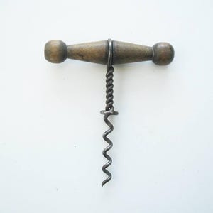 May include: A classic corkscrew featuring a wooden handle and a metal spiral. The handle is a light brown hue, with rounded ends. The metal spiral is dark grey and has a twisted design.