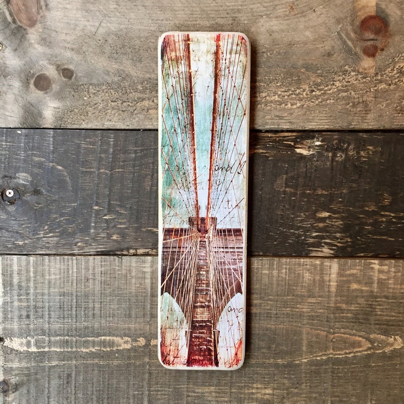 K&ouml;nnte beinhalten: Ein Vintage-Bild einer Br&uuml;cke in Rot-, Wei&szlig;- und Blaut&ouml;nen. Das Bild ist auf einer Holztafel mit einer abgenutzten Oberfl&auml;che gedruckt. Der Text "and I" ist auf der Tafel sichtbar.