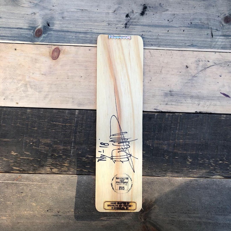 K&ouml;nnte beinhalten: Ein Holzschild mit einer schwarzen Unterschrift und dem Datum "NY 1-18". Das Schild ist mit "Brooklyn Art Factory" und "GIFTS" gestempelt.