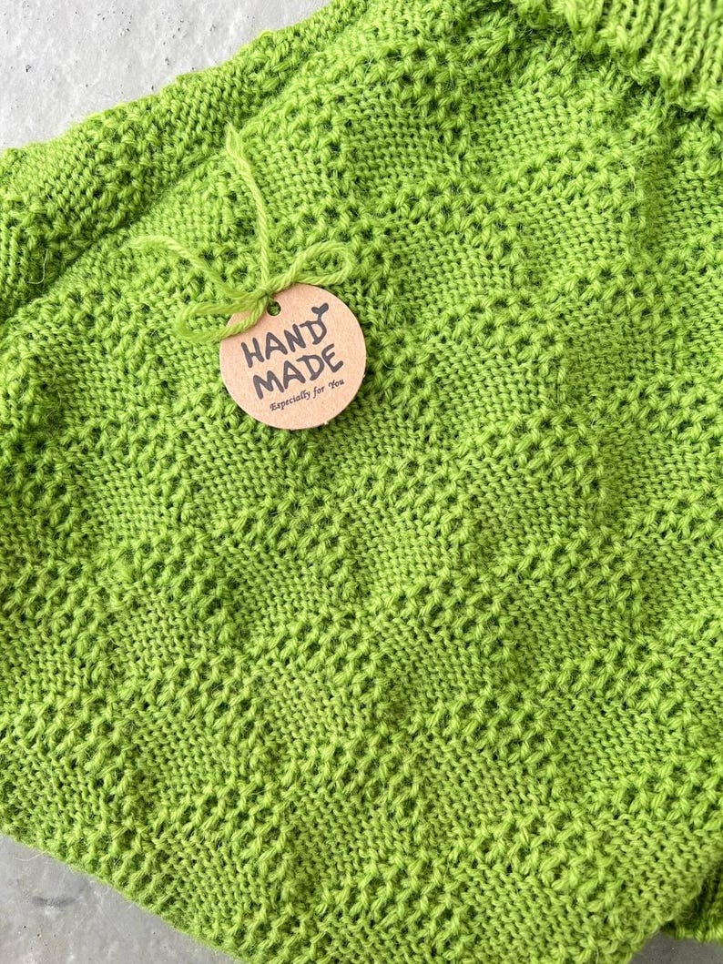 May include: A green knitted blanket with a brown tag that says "HAND MADE Especially for you".