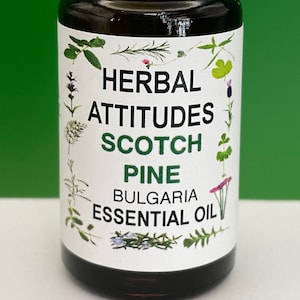 May include: A small brown glass bottle with a white cap, labeled "HERBAL ATTITUDES SCOTCH PINE BULGARIA ESSENTIAL OIL". The label features a variety of green leaves and flowers.