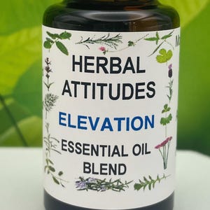 May include: A dark amber glass bottle with a white cap, labeled "HERBAL ATTITUDES ELEVATION ESSENTIAL OIL BLEND." The label features botanical illustrations and text. The bottle is filled with a dark liquid.