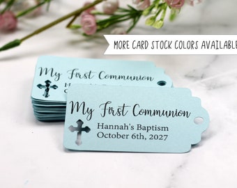 May include: Light blue tags with the text "My First Communion" and a cross cutout. The tags also include the text "Hannah's Baptism October 6th, 2027". The image also includes the text "MORE CARD STOCK COLORS AVAILABLE!"