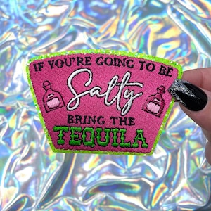 May include: A pink embroidered patch with the text "If You're Going To Be Salty Bring The Tequila." The patch has a green border and features two tequila bottle illustrations.