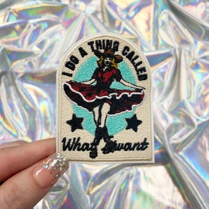 May include: Embroidered patch with a vintage design. The patch features a woman in a red dress and cowboy hat, with the text "I DO A THING CALLED What I want" in black lettering. Two black stars are on the patch.