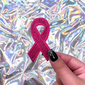 Op de afbeelding: Een roze lint met strass, een symbool voor bewustwording van borstkanker.