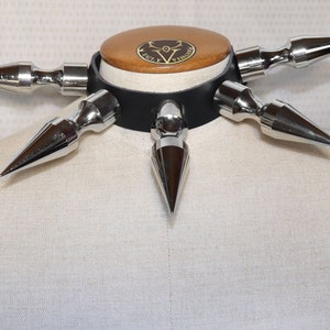 Könnte beinhalten: Ein schwarzes Lederhalsband mit sechs silbernen Spikes. Das Halsband befindet sich auf einer weißen Puppe.