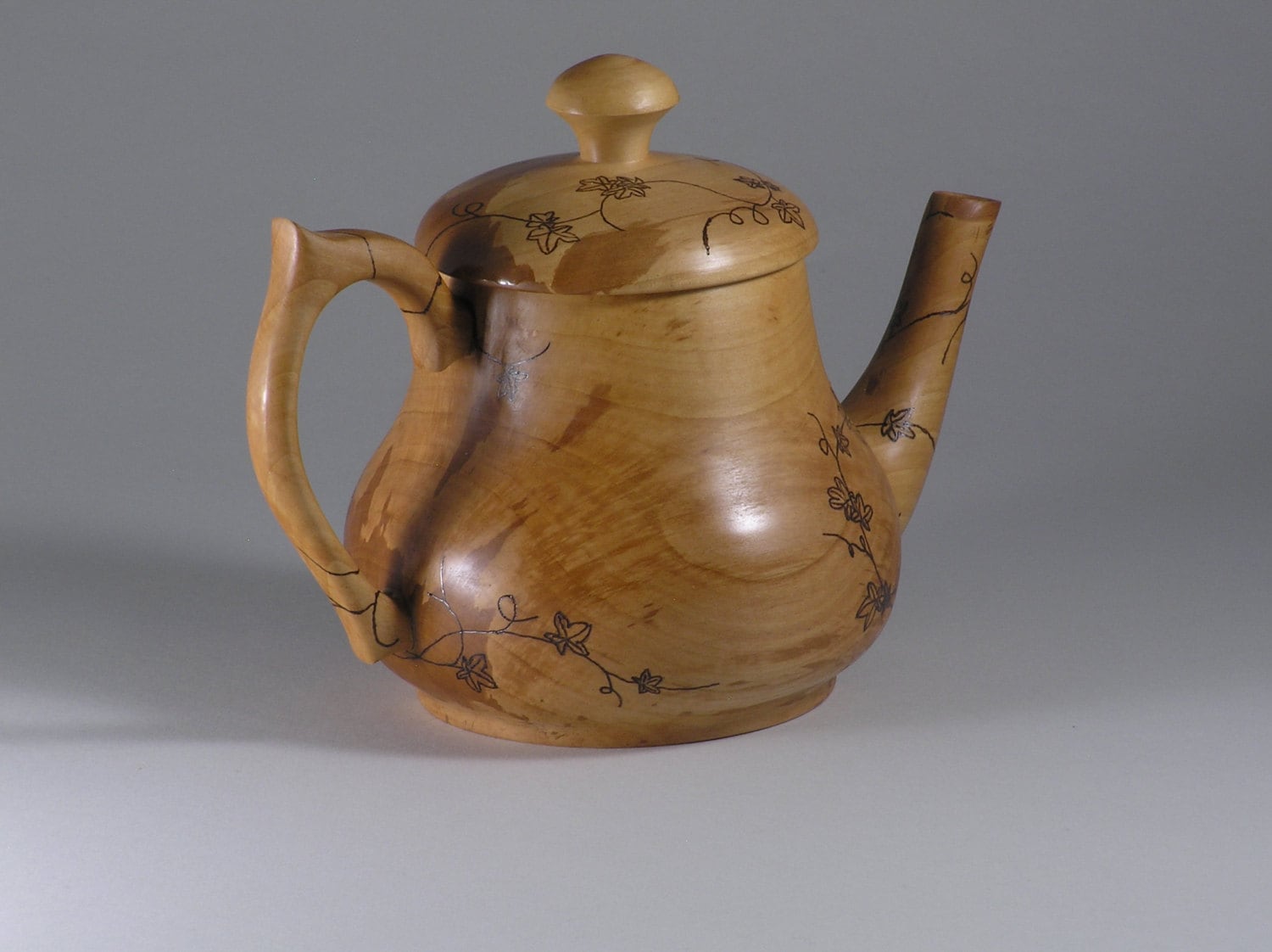 Wood teapot with a vine design