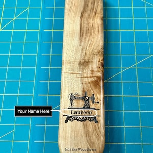 May include: A wooden seam ripper with a sewing machine design and the text "Laureen" engraved on it. The ripper is made by Jack the Wood Ripper in Alvaton, Kentucky.