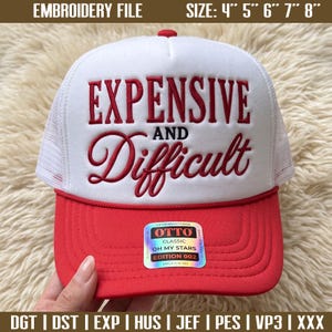 Peut inclure: Une casquette trucker blanche et rouge avec le texte brodé en rouge Expensive and Difficult et le mot AND en noir. La casquette présente une visière rouge, un filet blanc à l'arrière et un autocollant sur la visière indiquant OTTO CLASSIC OH MY STARS EDITION 002.