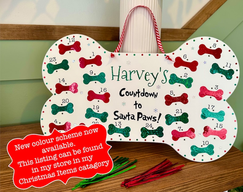 May include: A white wooden dog bone shaped Christmas countdown calendar with red and green glitter bones. The calendar is personalized with the name "Harvey's Countdown to Santa Paws!"