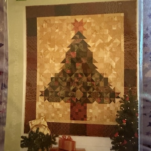 May include: A quilting pattern titled O' Christmas Tree by Bee Creative Studio. The cover features a patchwork quilt design of a Christmas tree in shades of brown, green, and gold, with a finished size of 60 inches by 69 inches printed on it.