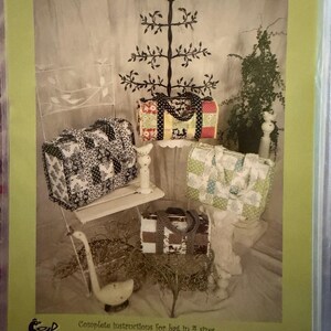 May include: A sewing pattern cover titled No. 93 The Miranda Mailbag by Serendipity Studio. The image displays four quilted fabric bags in different patterns and colors, including black and white, floral, and green, with text stating complete instructions for bag in 4 sizes.