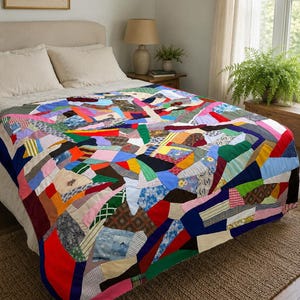 May include: A colorful patchwork quilt with a variety of fabric patterns and colors, including red, blue, green, and yellow. The quilt is spread over a bed with a neutral-colored headboard and pillows. The quilt's dimensions are approximately 80 inches by 90 inches.
