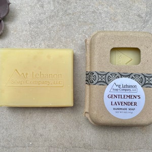 May include: A bar of handmade soap in a cardboard box. The soap is labeled "Gentlemen's Lavender" and "Mt Lebanon Soap Company, LLC". The soap is a light yellow color.