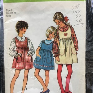 Può includere: Modello di cucito Simplicity numero 0901 per abiti da bambina. Il modello include tre diversi stili di abiti, tutti con una stampa a quadri. Il modello è per le taglie 8, con un busto di 27 pollici.