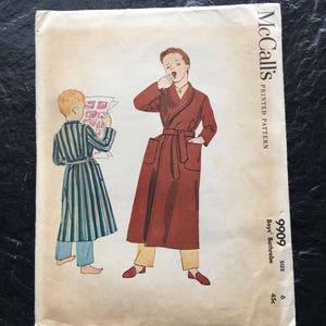 May include: Vintage McCall's sewing pattern for a boy's bathrobe. The pattern is for size 6, 45c. The pattern shows two boys wearing bathrobes, one in a striped bathrobe and the other in a solid red bathrobe.