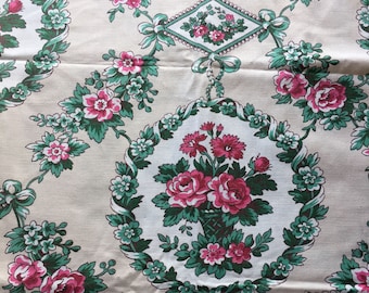 May include: A white fabric with a repeating pattern of pink and green floral bouquets. The bouquets are surrounded by green leaves and white flowers. The fabric has a vintage look.