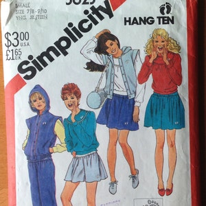 May include: Simplicity sewing pattern number 5623 for a Hang Ten youth outfit. The pattern includes three different looks: a blue tracksuit with a yellow vest, a blue sweater with a white collar and a light blue skirt, and a red sweater with a blue skirt. The pattern is for stretch knits only and includes a pick-a-knit rule on the envelope back.
