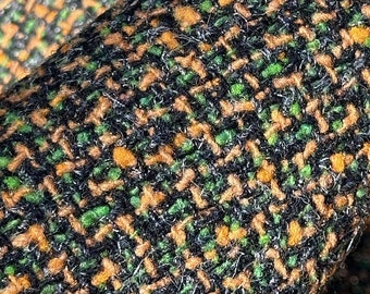 May include: Close-up of a black, green, and orange tweed fabric with a woven pattern.