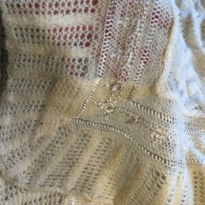 May include: White crocheted fabric with a decorative silver trim. The fabric has a delicate, open-weave pattern.