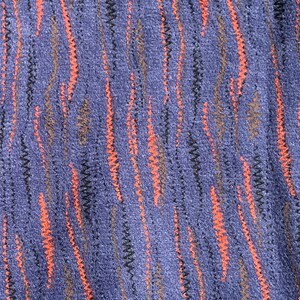 May include: A close-up of a blue fabric with a textured pattern of orange and brown lines.