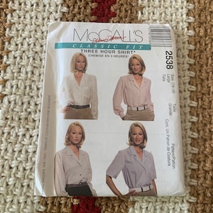 May include: A McCall's sewing pattern for a classic fit three-hour shirt. The pattern is for sizes 16-18 and is labeled as "2538". The pattern shows a woman wearing a white shirt with a collar and long sleeves.