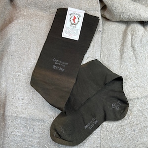 Op de afbeelding: Een paar donkerbruine sokken met de merknaam "Winged Foot Hose" en de tekst "Elastic reinforced Garter Top Split-Stop" op de ene sok en "Milanese Style Double Sole" en "441C 10" op de andere sok.