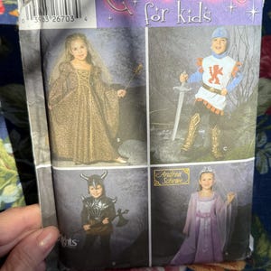 May include: Simplicity Costumes for Kids sewing pattern. The pattern features four different costume designs: a medieval princess, a knight, a Viking, and a medieval knight. The pattern includes sizes 3, 4, 5, 6, 7, and 8.