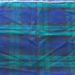 Könnte beinhalten: Ein blauer und grüner karierter Stoff mit weißem Rand. Der Stoff ist in der Mitte gefaltet und hat eine weiche, flauschige Textur.