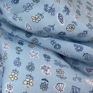 May include: A light blue fabric with a white and yellow floral pattern. The fabric is soft and has a subtle sheen.