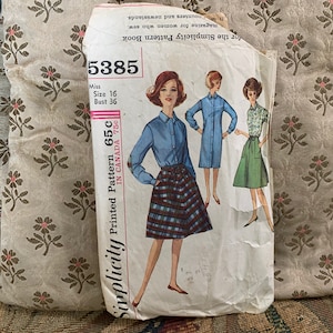 May include: Vintage Simplicity sewing pattern number 5385 for a dress. The pattern is for a miss size 16 with a bust of 36 inches. The pattern is printed on white paper with a black and red plaid design. The pattern is for a dress with a collar and short sleeves. The pattern is for a dress with a skirt that is slightly flared. The pattern is for a dress that is knee-length.