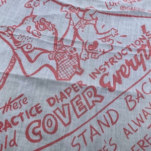 May include: Red text on a white fabric background with a cartoon illustration of a person holding a diaper. The text reads "Practice Diaper Cover Instructions Everything Stand Back Always More There That"