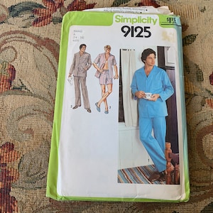 Könnte beinhalten: Simplicity Schnittmuster Nummer 9125 für Pyjamas. Das Schnittmuster zeigt drei verschiedene Pyjama-Stile, darunter ein blauer Pyjama-Anzug mit einem Hemd mit Knöpfen und einer Hose.