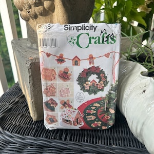 Può includere: Modello Simplicity Crafts numero 9768 per una ghirlanda natalizia, una casetta di pan di zenzero e altre decorazioni. Il modello include istruzioni per realizzare una casetta di pan di zenzero, una ghirlanda, una ghirlanda e altri ornamenti. Il modello è di Blaine Hegyl.