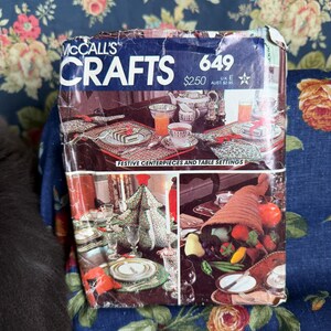 May include: A McCall's Crafts 649 pattern envelope featuring festive centerpieces and table settings. The cover displays photographs of decorated dining tables, a fabric Christmas tree, and a cornucopia filled with various fruits and vegetables.