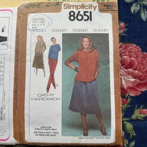 Può includere: Cartamodello vintage Simplicity 8651 con modelli di Cathy Hardwick. Il modello include le taglie 6 e 8 ed è per maglieria elasticizzata. La copertina mostra illustrazioni dei capi finiti, tra cui una gonna e un top.