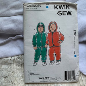 Op de afbeelding: Een naaipatroon voor een kinder jumpsuit met capuchon. Het patroon is voor de maten T1-T2-T3-T4. Het patroon is van Kwik Sew Pattern Co. Inc. en is nummer 2260.
