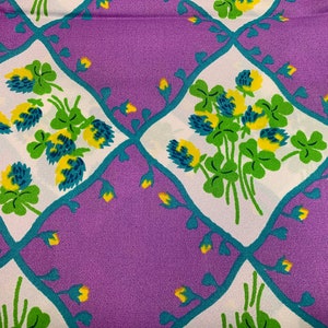 Pu&ograve; includere: Tessuto viola con un motivo di trifoglio bianco e verde. Il trifoglio &egrave; contornato di blu turchese e ha centri gialli.